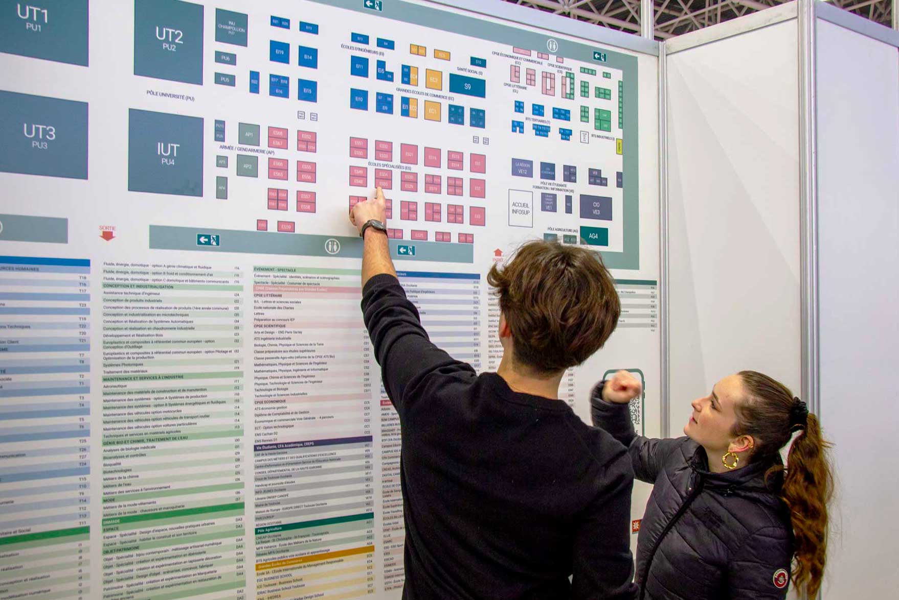 2 personnes en face du plan du salon infosup en train de pointer du doigt un stand
